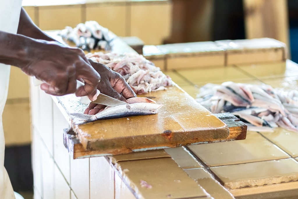 Man slicing flying fish inside a market in Barbados