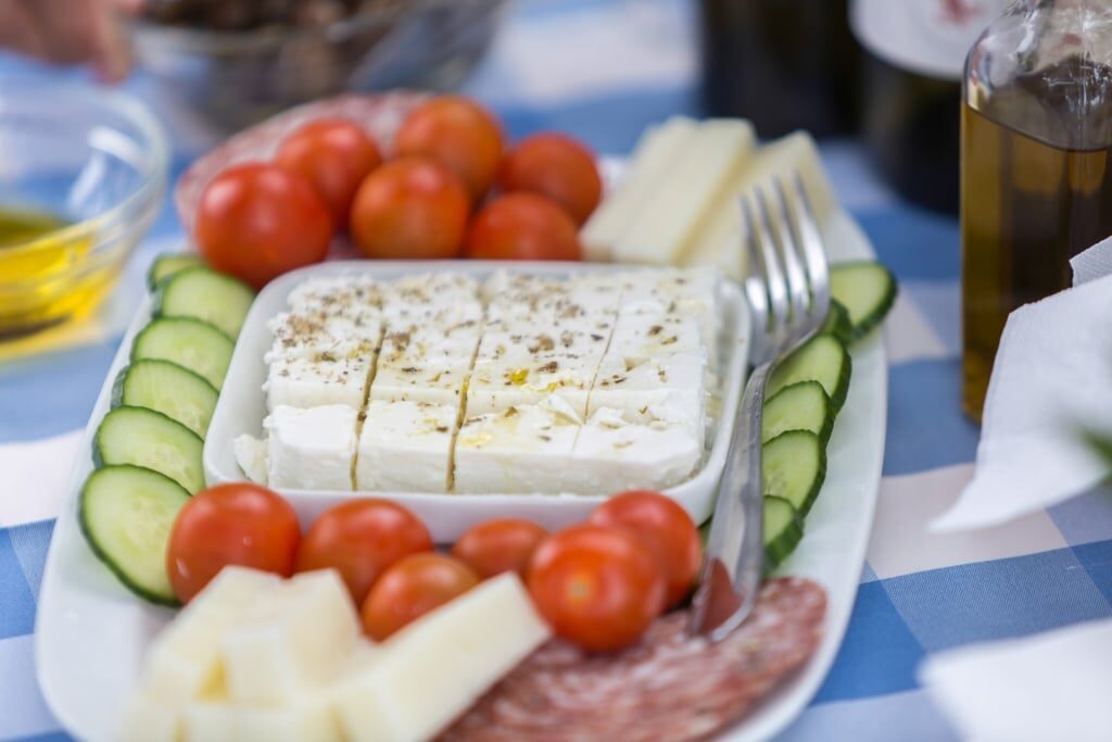 Feta cheese on a platter with cucumbers and tomato