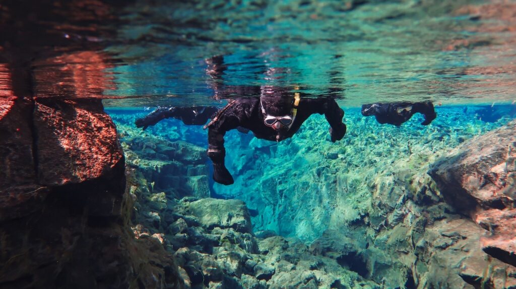 People snorkeling in the Silfra fissure in Thingvellir National Park, Iceland