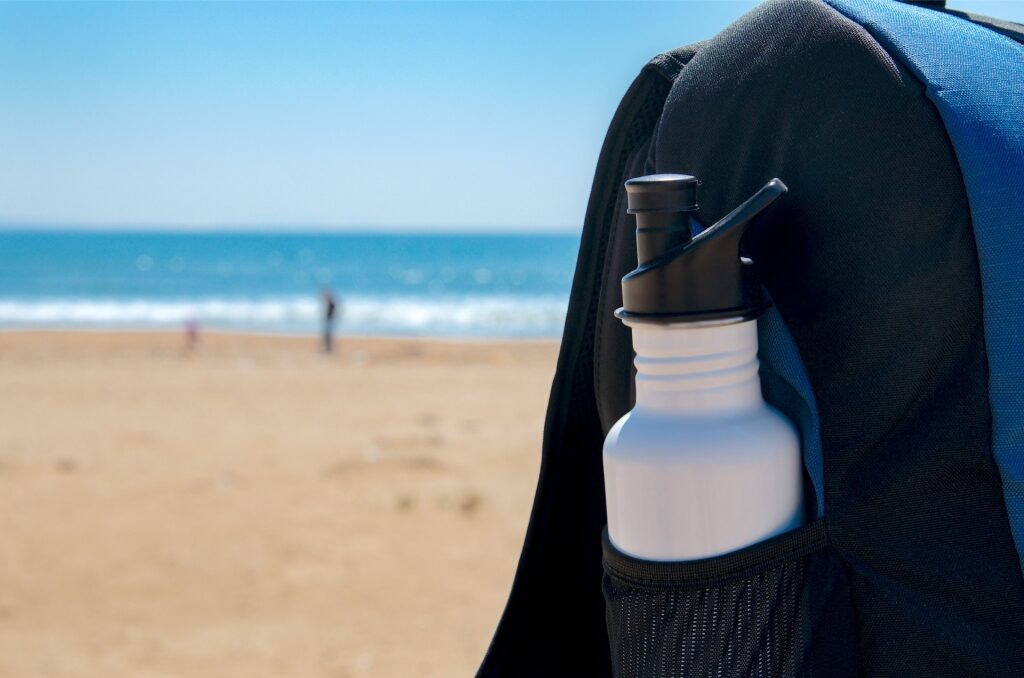 White reusable water bottle at the beach