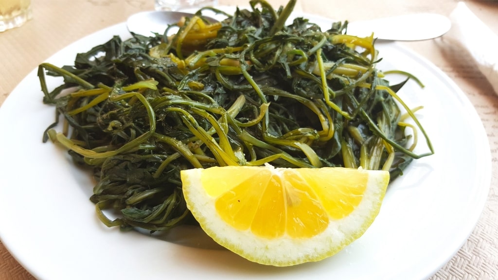 Plate of horta greens with lemon on the side