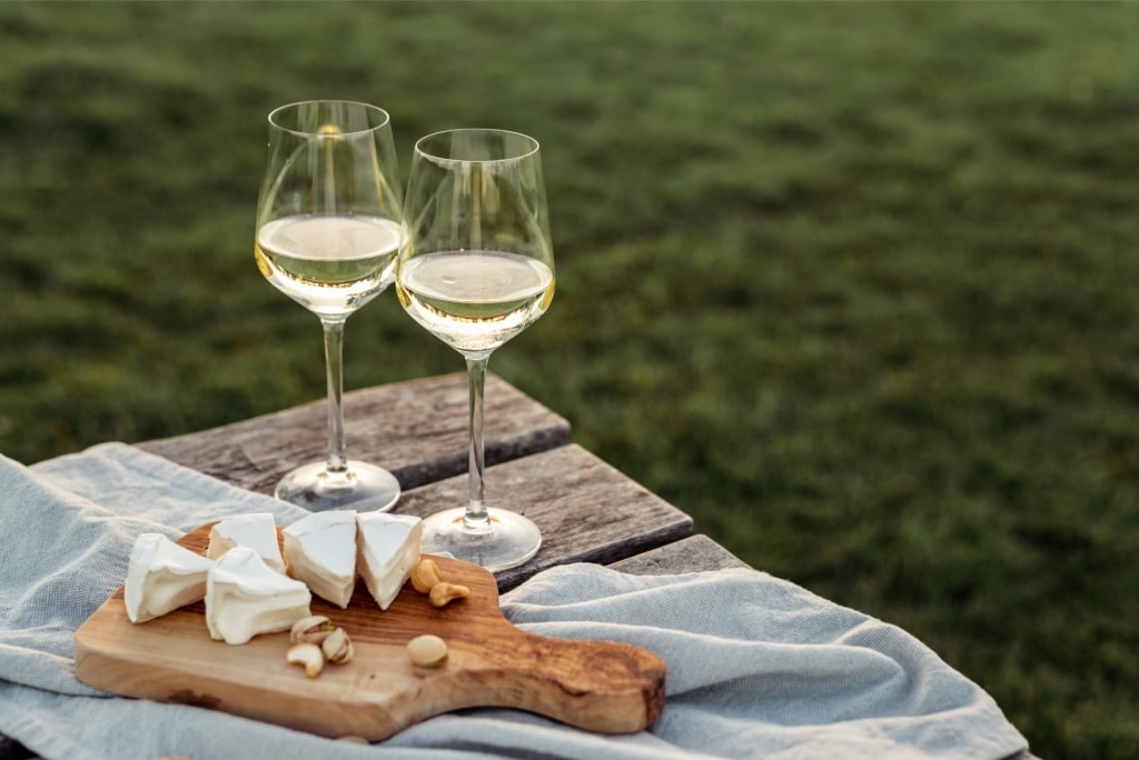Wine glasses on a table with cheese on a platter