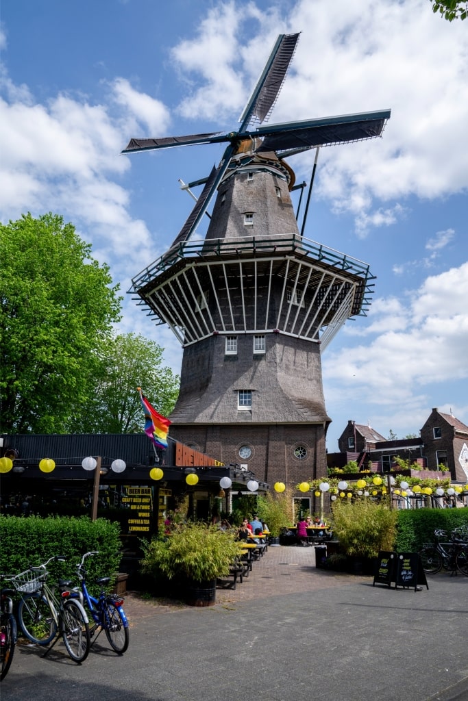 Scenic view of De Gooyer windmill with plants and parked bicycles