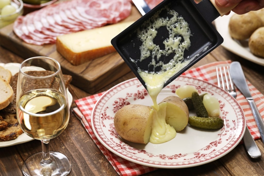 Melted raclette cheese being poured over potatoes