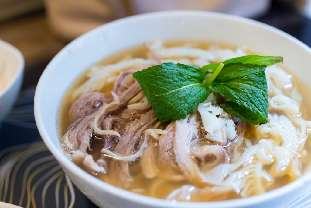 Close-up of traditional Vietnamese pho with beef, noodles, and fresh herbs