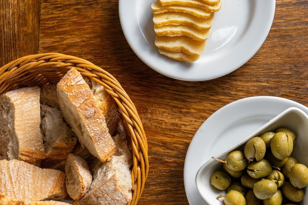 Traditional Portuguese couvert appetizer with bread, olives, and cheese served on a rustic table