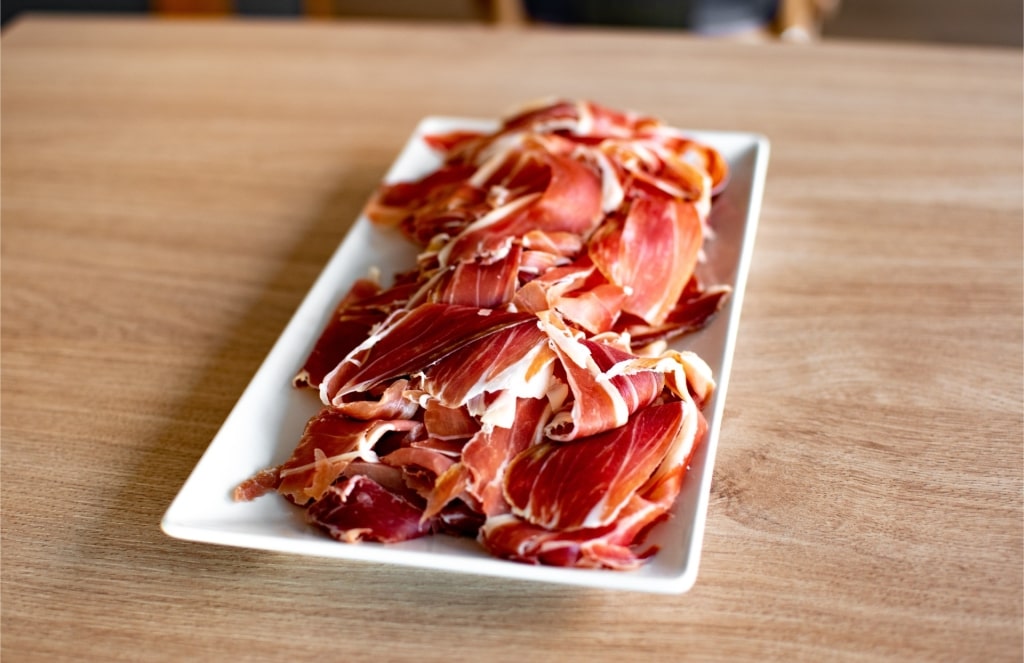 Thinly sliced jamón ibérico served on a white plate
