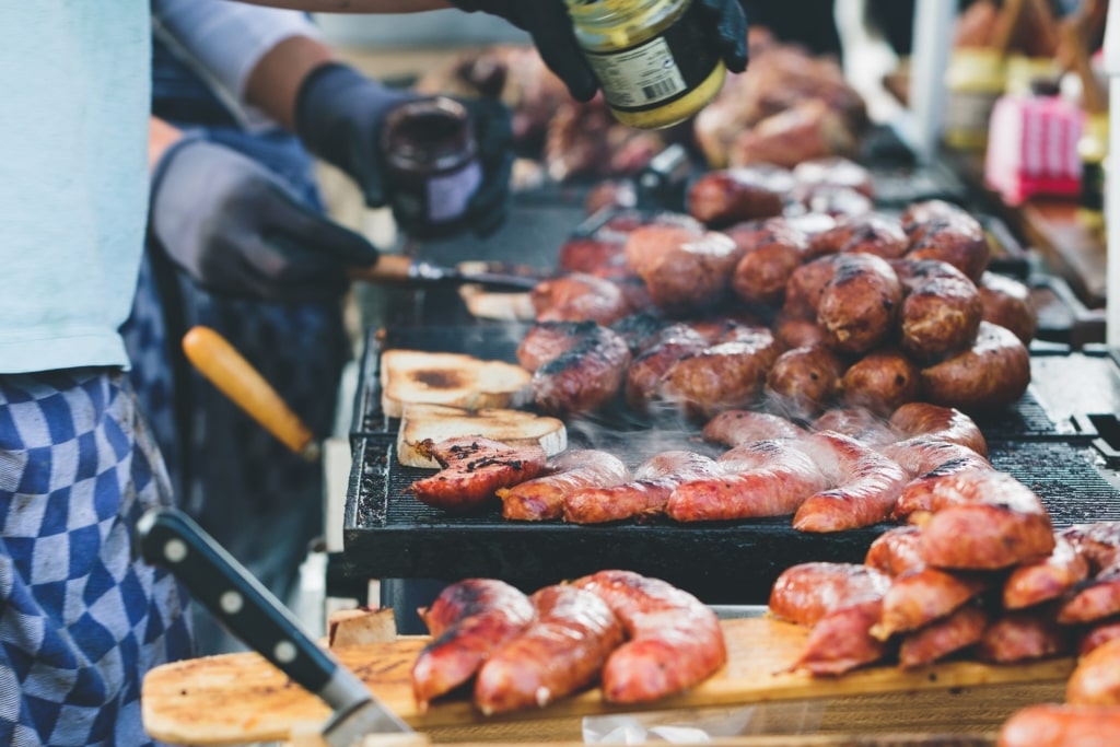 Street vendor cooking fried sausages and toasts at Amsterdam Sunday market