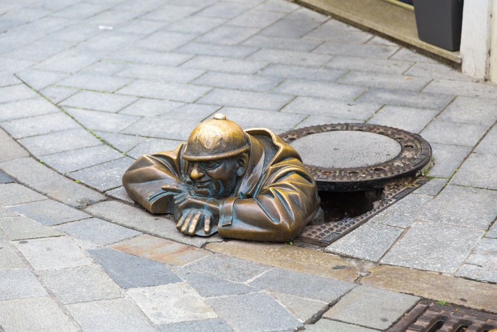Famous Cumil statue poking head out of manhole in Bratislava Old Town