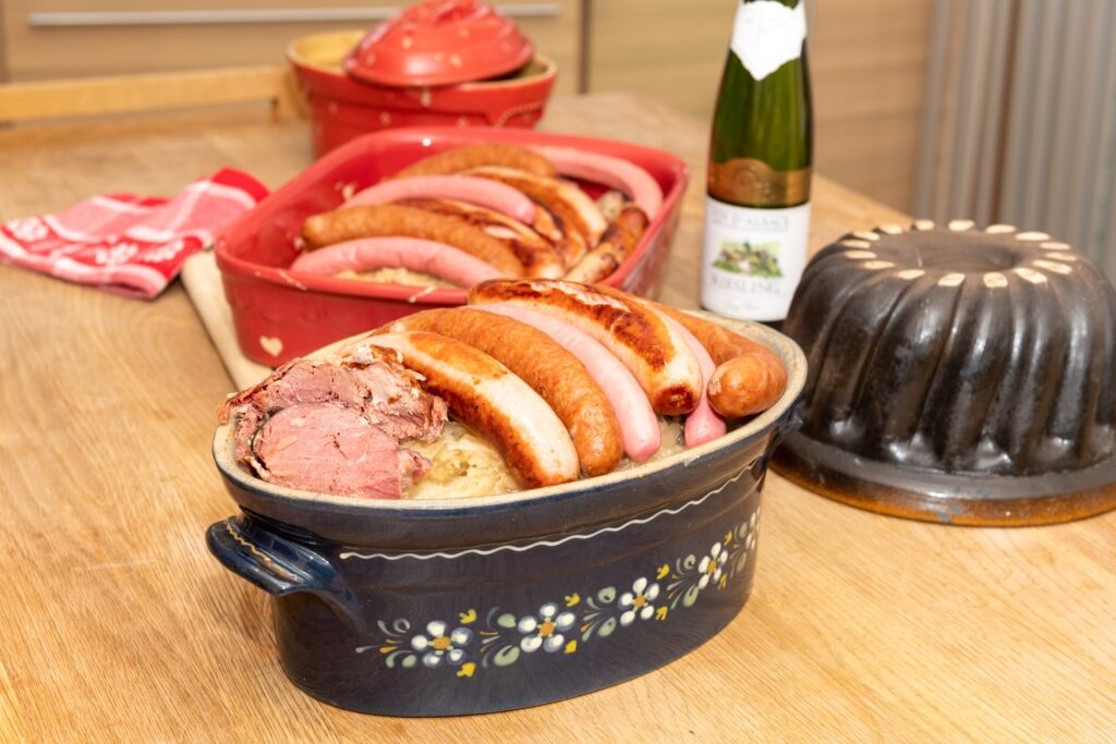 Traditional Alsatian Choucroute garnie with sauerkraut and Riesling wine on table