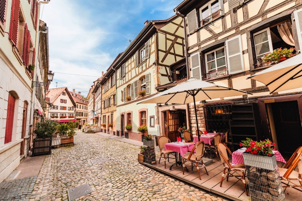 Charming cobblestone street in Strasbourg with outdoor café seating and historic buildings