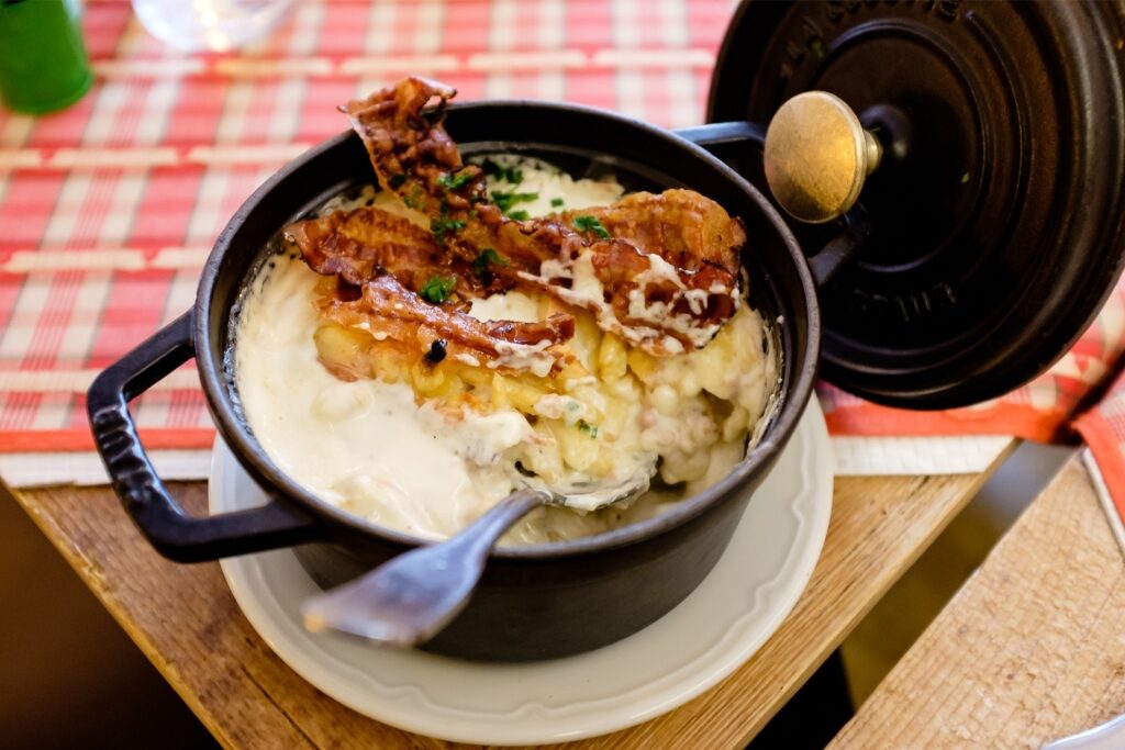 Traditional Alsatian Spätzle pasta with bacon served in a black pan