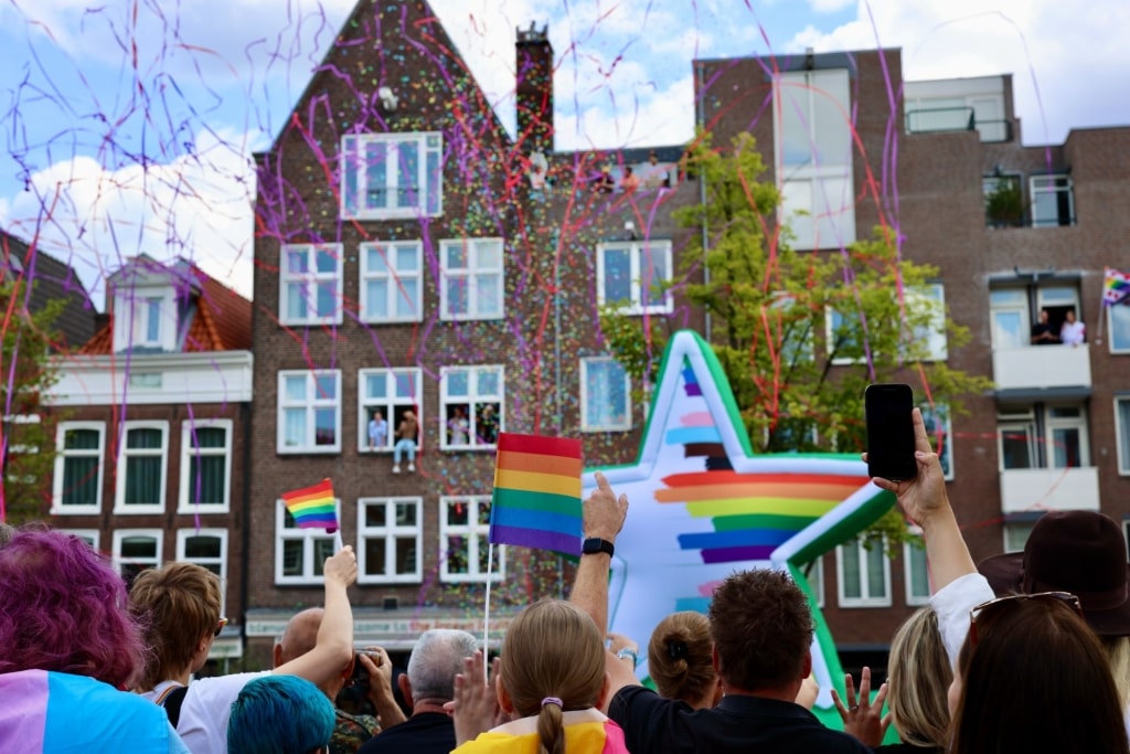Crowds celebrating Amsterdam Pride with rainbow flags and decorations