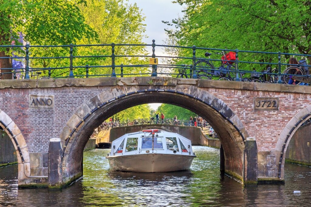 Canal tour boat passing under a bridge along Amsterdam waterways