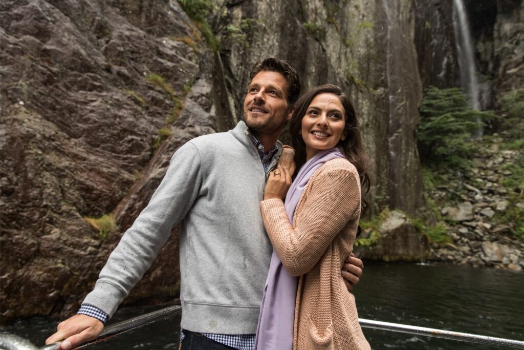 Tourist couple standing by Lysefjord with scenic cliffs in Norway
