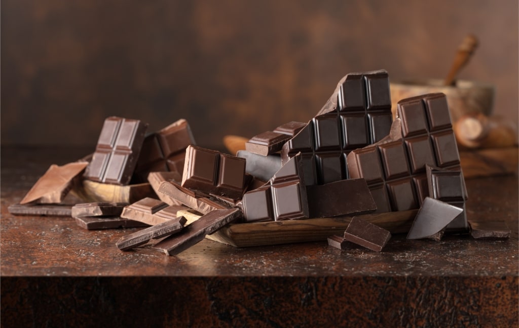 Broken pieces of bitter and milk chocolate bars on a brown vintage background