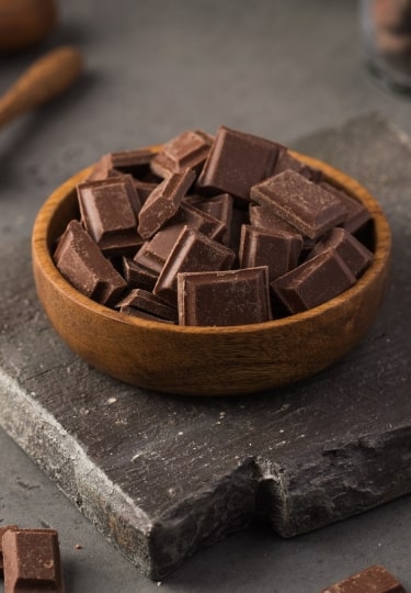 Milk chocolate pieces in a wooden bowl