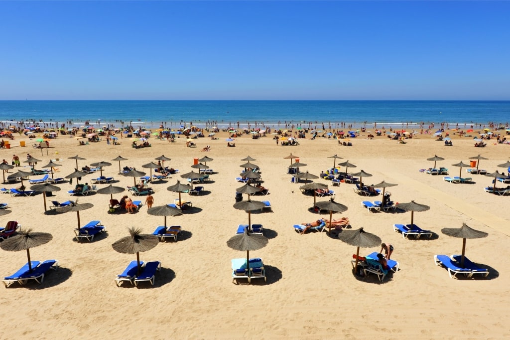 Sunny day with visitors relaxing and sunbathing at Playa de la Victoria, Cádiz