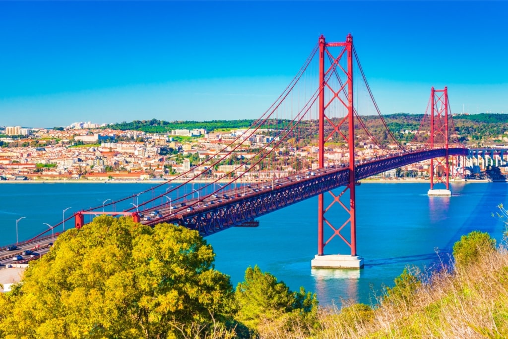 Aerial shot of Lisbon’s Ponte 25 de Abril with the city skyline and river in Portugal