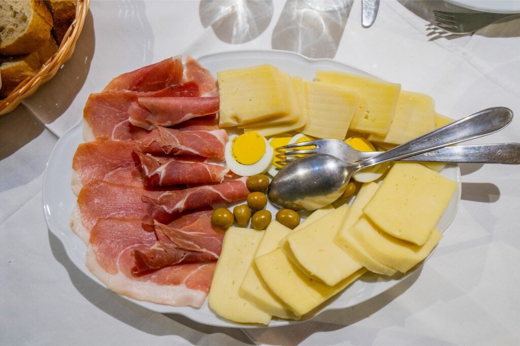 Njeguški Sir cheese served with olives, egg, and cured ham