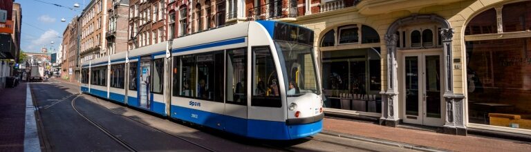 Public transport tram driving through Amsterdam city street