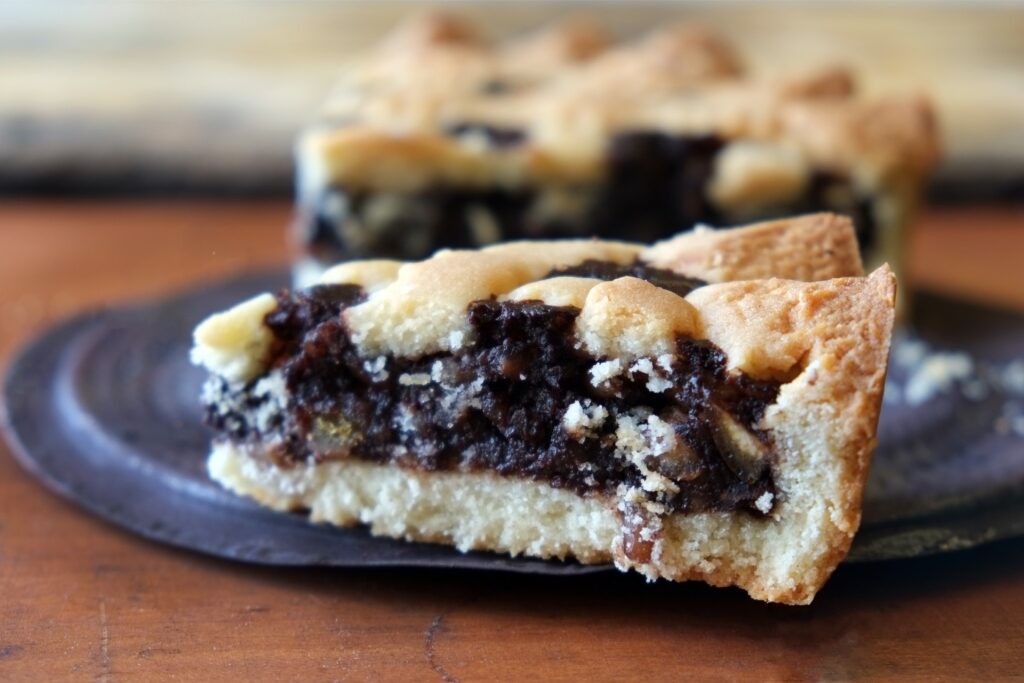 Slice of Torta co’ bischeri, a traditional Tuscan cake filled with chocolate, rice, and nuts