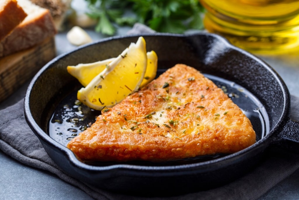 Saganaki in a pan with lemon wedges on the side