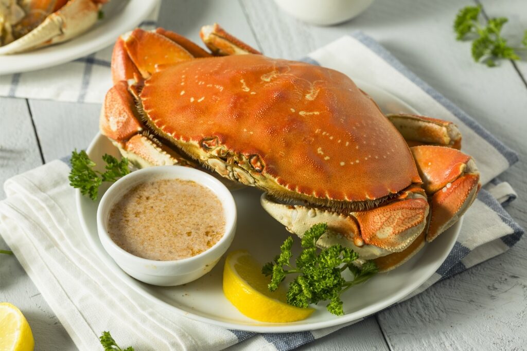 Dungeness crab on a plate with sauce and lemon on the side