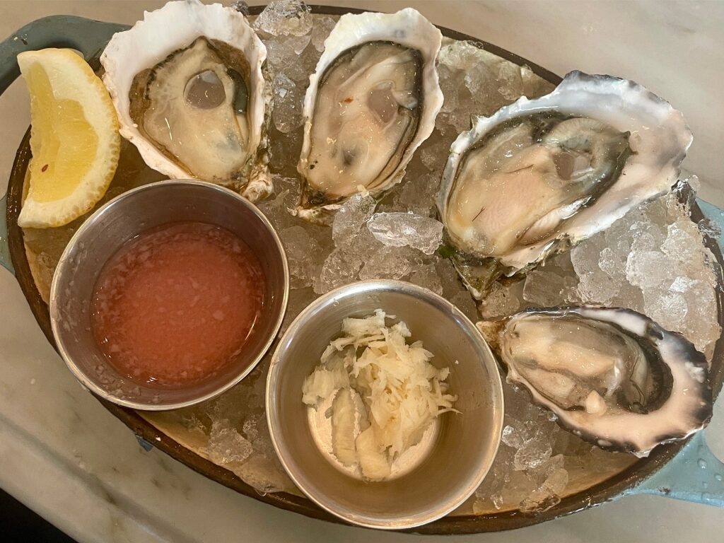 West Coast oysters on a platter with sauce on the side