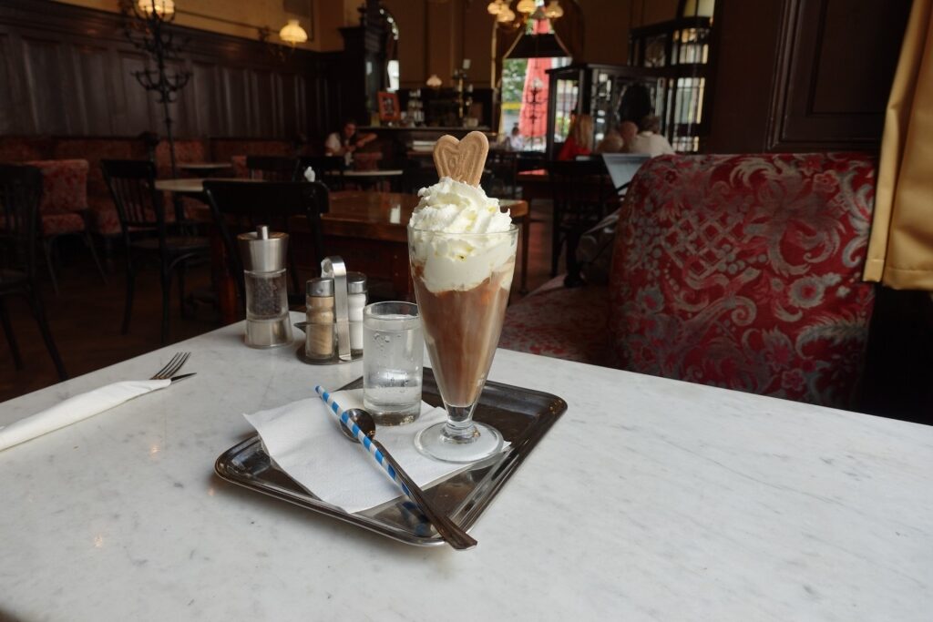 Viennese coffee topped with whipped cream and cookie in a traditional café