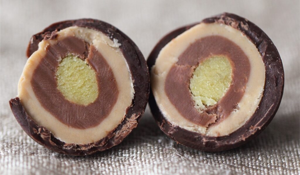 Close-up of a halved Mozartkugel showing layers of chocolate, marzipan, and nougat