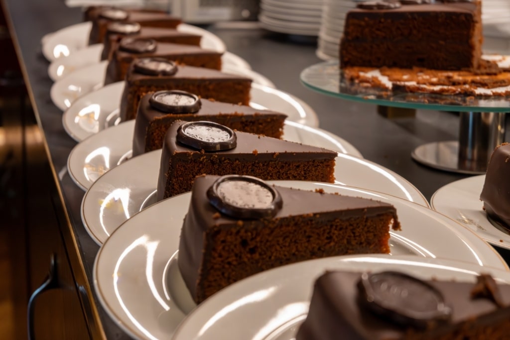 Several slices of Sacher-Torte chocolate cake on white plates