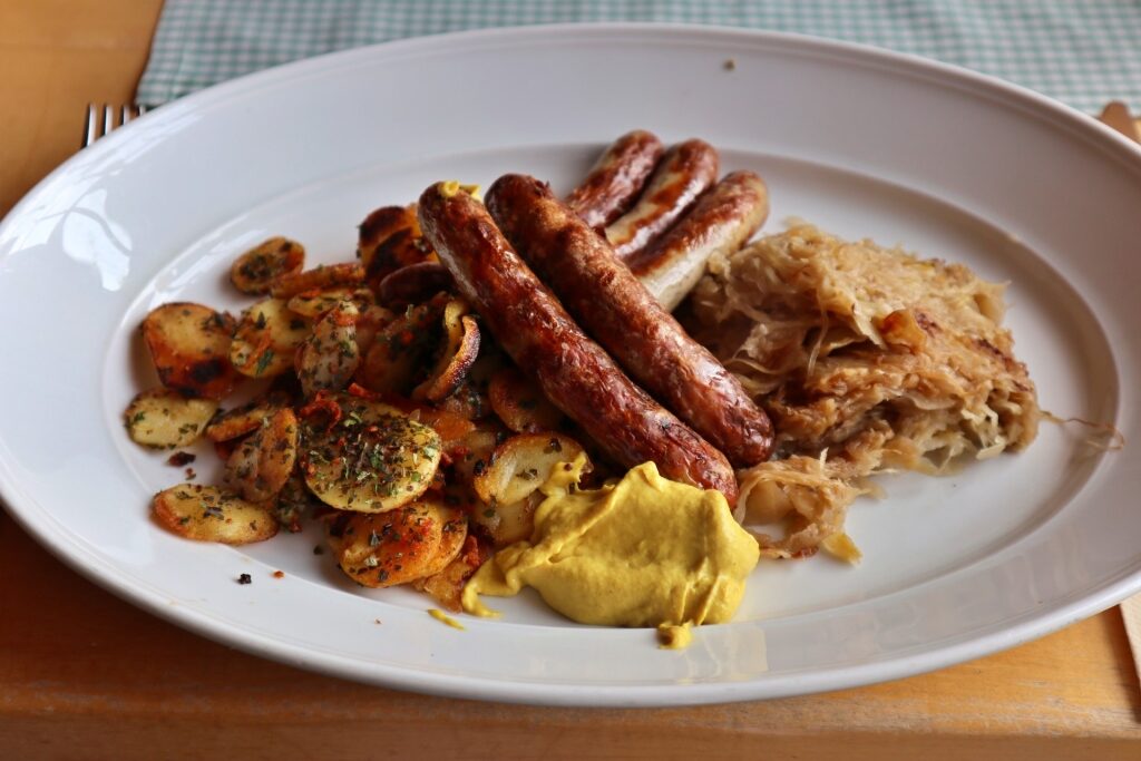 Traditional German meal of bratwurst sausages with baked potatoes and sauerkraut