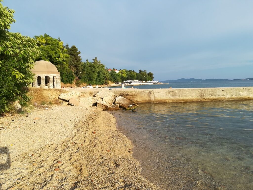 Kolovare Beach in Zadar, Croatia with a traditional domed stone structure along the shoreline
