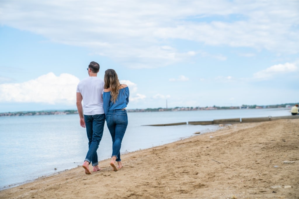 Couple walking on the sandy Queen’s Beach in Nin