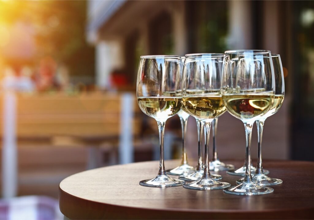 White wine being poured into glasses during an outdoor winery terrace tasting