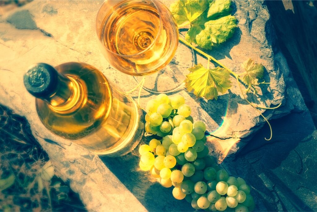 Top-angle shot of a white wine bottle and full glass with grapes