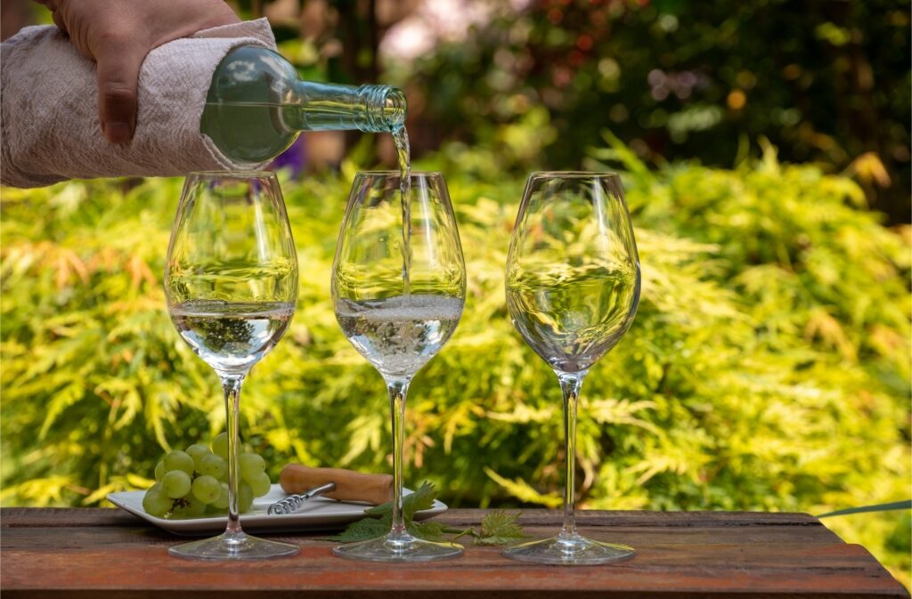 Refreshing white wine tasting on a sunny terrace with glasses being filled