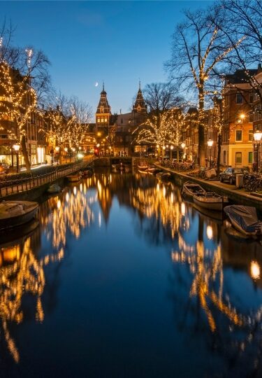 Amsterdam canal at night illuminated by streetlights and reflections on the water