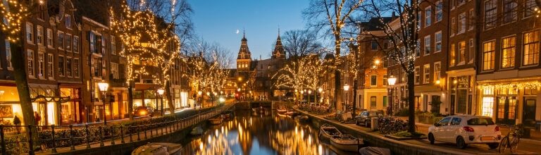 Amsterdam canal at night illuminated by streetlights and reflections on the water