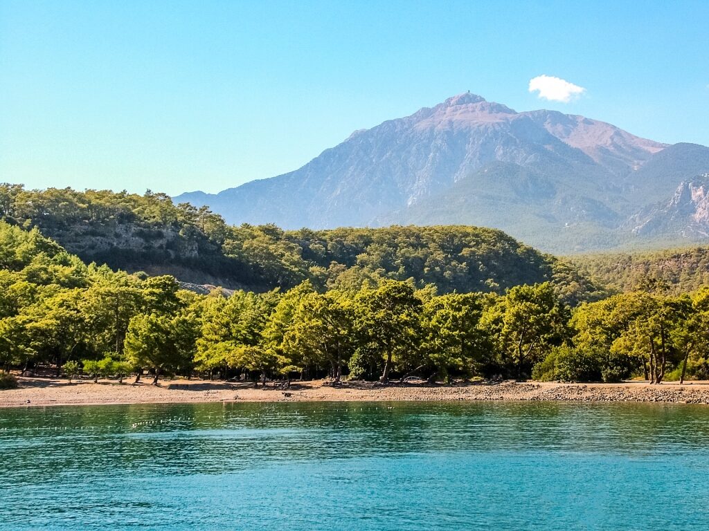 Scenic coastline of Çamyuva Beach with calm water and mountain backdrop