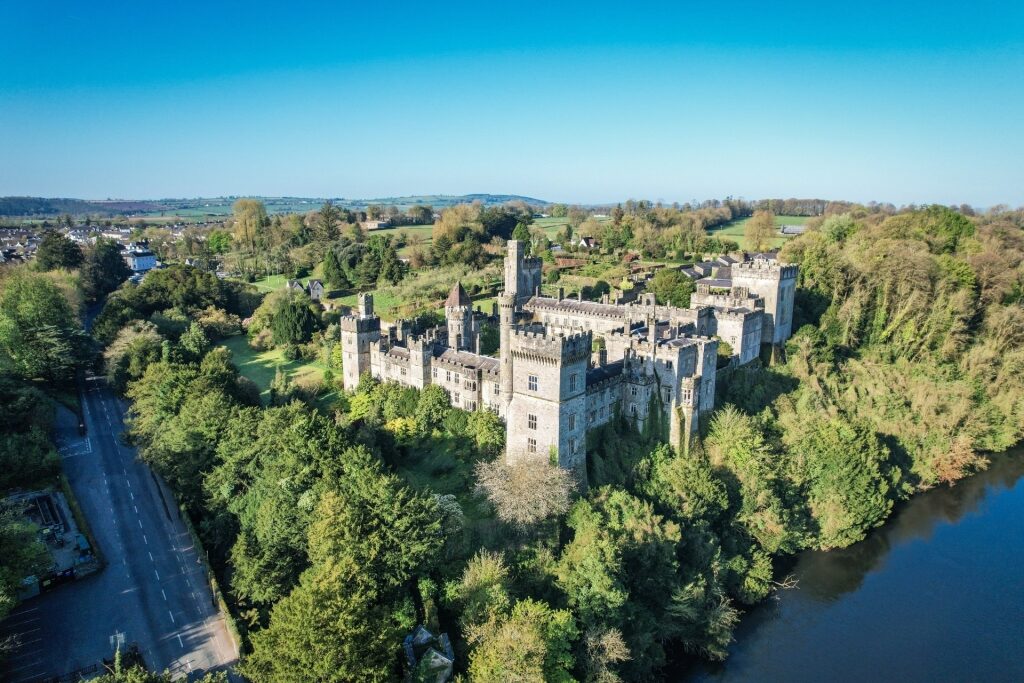 Aerial view of Lismore Castle surrounded by lush forest in Ireland