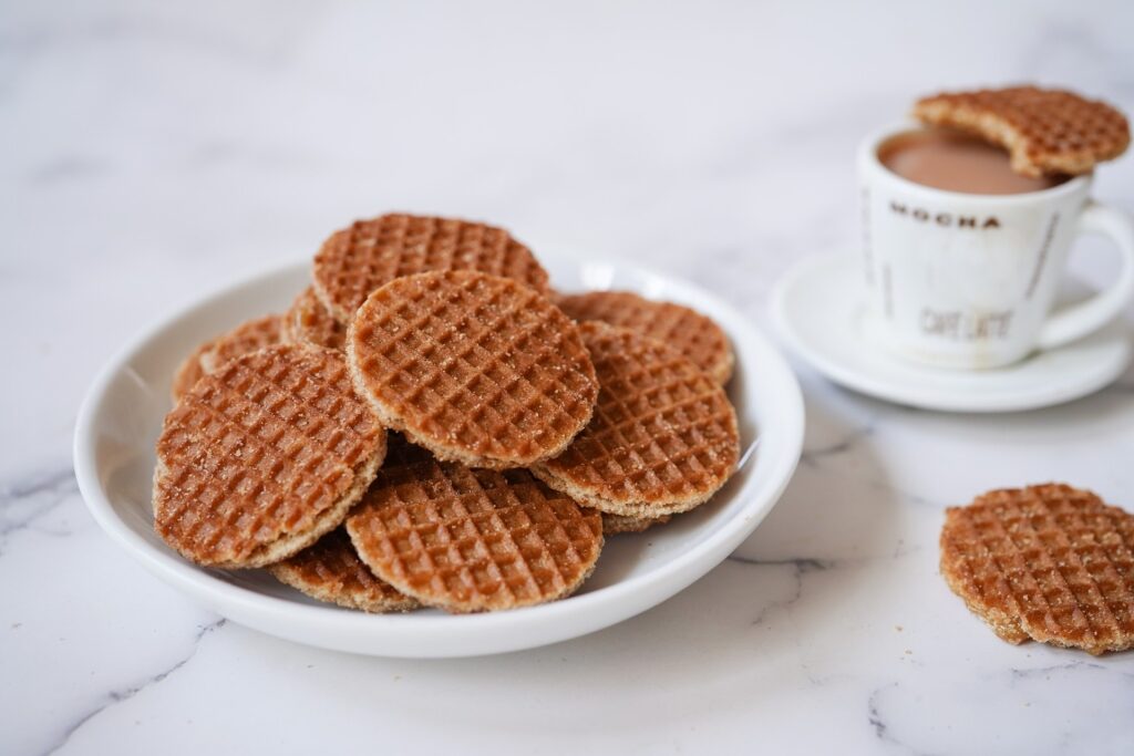 Stroopwafel on a white plate beside a cup of coffee