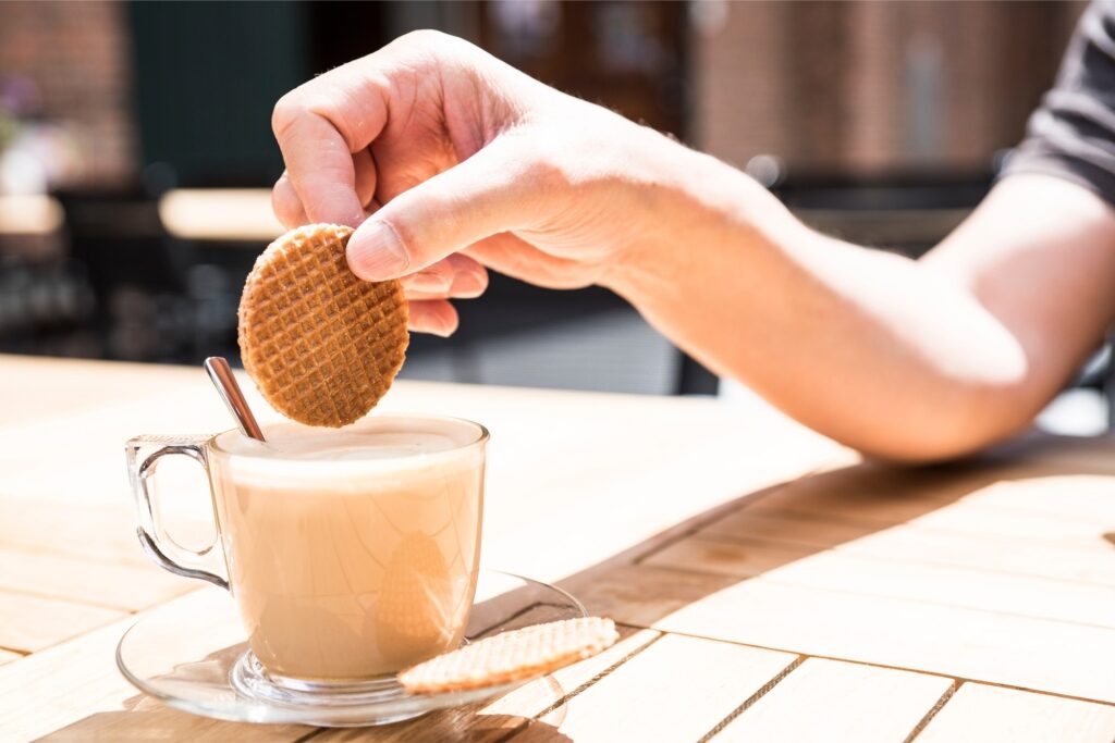 Crispy stroopwafel dipping in warm coffee for a sweet Dutch treat