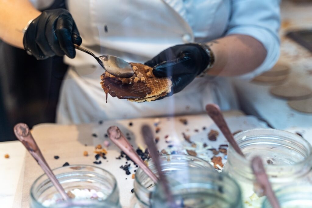 Street vendor drizzling sauce over fresh stroopwafel in Amsterdam