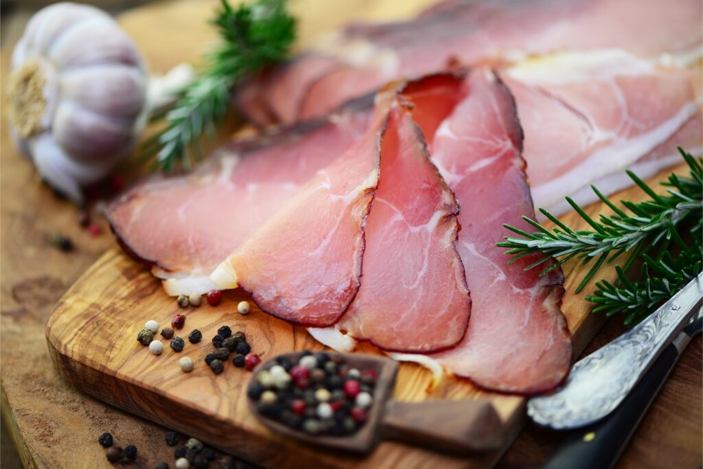 Sliced Black Forest ham arranged on a wooden cutting board