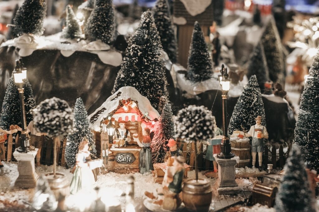 Snow-covered miniature wooden house with people at a Christmas market