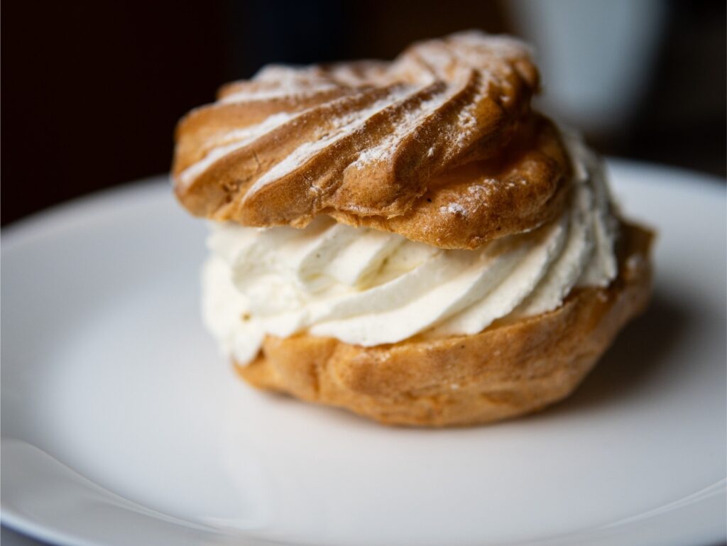 Close-up of a traditional German Windbeutel dusted with sugar