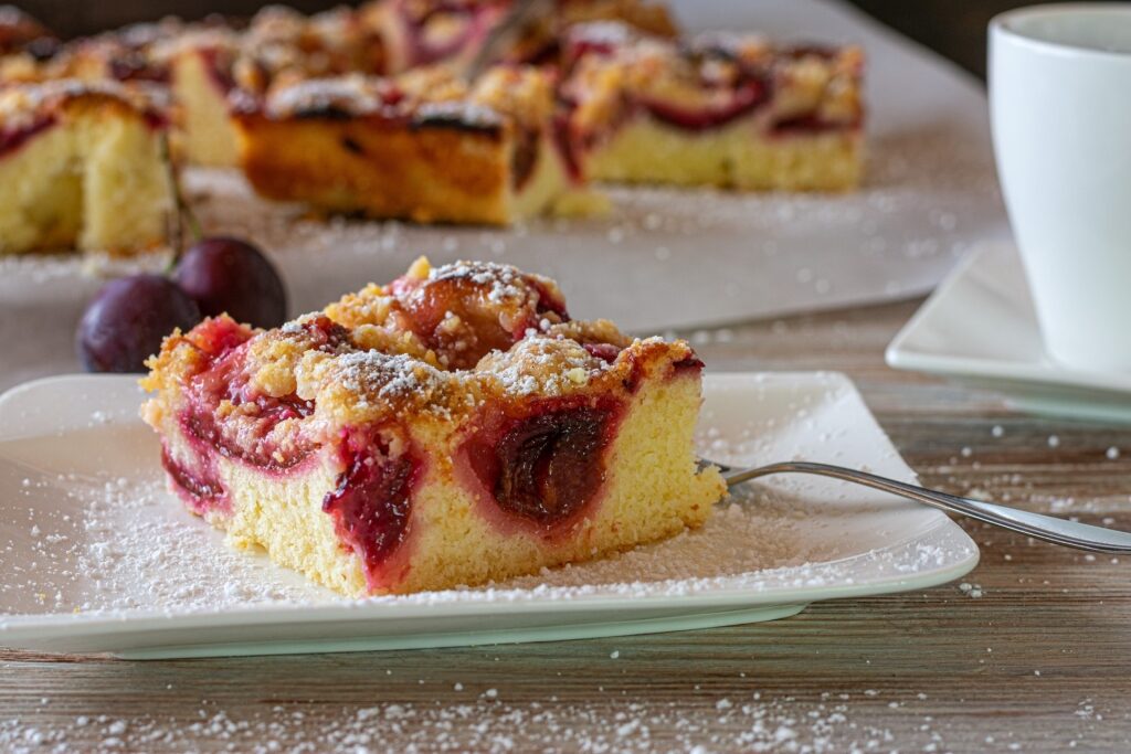 Slice of German Zwetschgenkuchen with baked plums on a plate