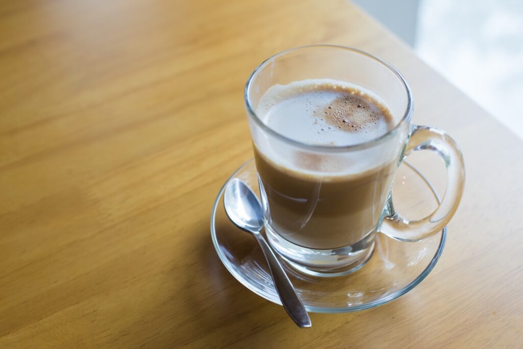 Caffè latte served in a glass cup on a wooden table